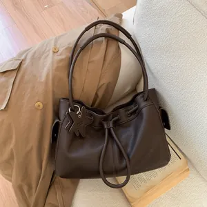 Macro detail of dark brown lychee texture tote bag with star charm and drawstring