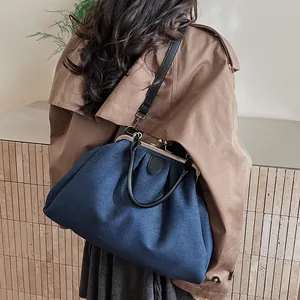 Detail of blue denim doctor bag with retro metal frame and black leather handles