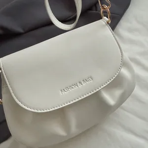 Détail de la sacoche plissée ivoire avec lettrage embossé et anneaux dorés chic
