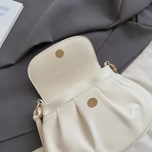 Détail du sac en cuir PU blanc crème avec texture plissée et fermoir magnétique rond