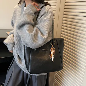 Detail of a large black tote bag with silver logo and ethnic-style beaded keychain