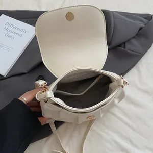 Structure interne du sac selle plissé beige avec poche zippée dorée et boucle aimantée