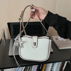 Detail of cream saddle bag with silver star charms and rotary metal lock closure