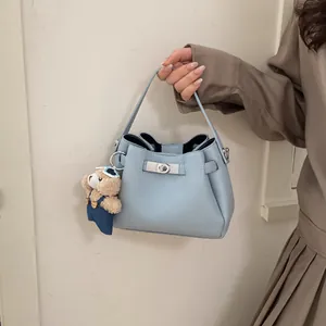 Detail of light blue bucket bag with silver twist lock and cute bear keychain charm