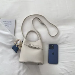 Dettaglio della mini borsa a secchiello off-white con trama in pelle martellata e orsetto
