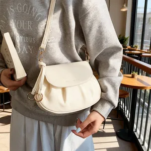 Détail du sac selle plissé crème avec anneau métallique et fermeture à rabat magnétique