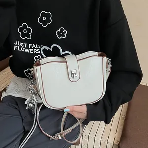 Close-up of cream white saddle bag with brown trim and silver heart tassel charm