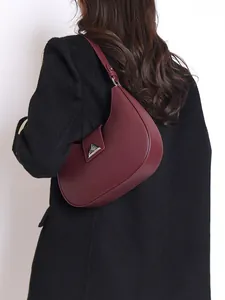 Chic burgundy crescent hobo bag with pebble leather and silver metal clasp on model