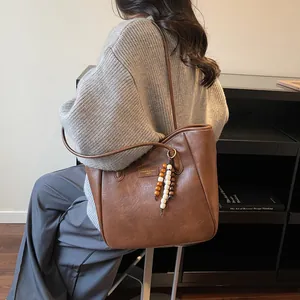 Close-up of vintage brown tote bag with leather texture and bead charm accessory