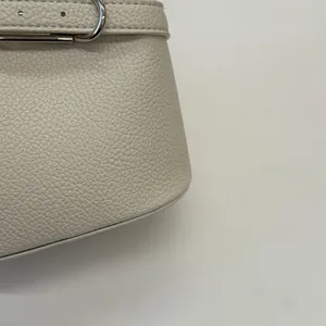 Dettaglio della borsa a secchiello bianco crema con pelle martellata e fibbia argentata