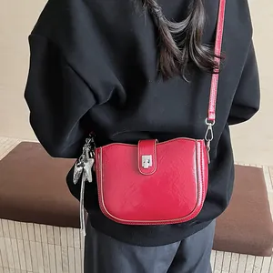 Close-up of a vintage red saddle bag with shiny leather, silver buckle and star charm detail