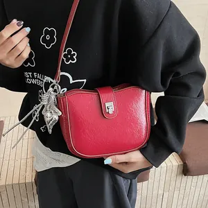 Close-up of bright red saddle bag with embossed faux leather and silver heart charm
