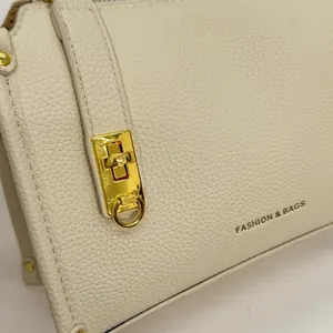 Macro shot of off-white lychee grain leather handbag with gold metal clasp and logo