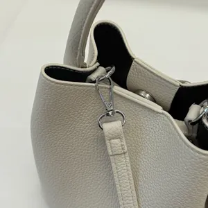 Dettaglio macro del gancio in metallo argento e pelle litchi sulla borsa a secchiello