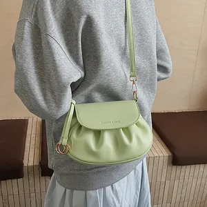Détail du sac bandoulière plissé vert menthe avec finitions dorées et texte embossé