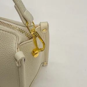 Detail of cream lychee grain leather handbag with golden rotating clasp and metal zipper