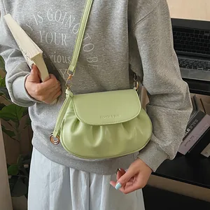 Détail du sac selle vert menthe avec plis, boucle dorée et bandoulière fine en PU
