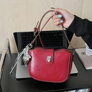 Detail of red saddle bag featuring a polished texture and heart-shaped silver pendant