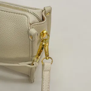 Detail of beige pebble leather handbag featuring gold-tone hardware and silver zipper