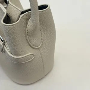 Dettaglio borsa a secchiello in pelle bianca martellata con lucchetto d'argento e manico