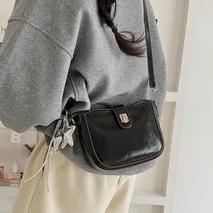 Detail of black saddle bag with glossy finish and silver star charm detail