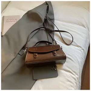 Detailed view of brown leather handbag capacity showing a smartphone for size reference