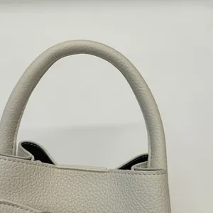 Dettaglio del manico circolare e della trama della pelle a grana litchi della borsa a secchiello