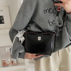 Detail of black glossy saddle bag with silver hardware and star charm on model