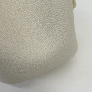 Dettaglio della borsa a secchiello bianco crema con pelle a grana e bordo soffice