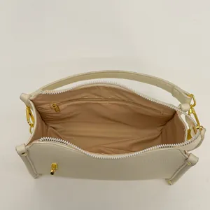 Detail showing the cream Boston bag's interior structure with zipper pocket and metal hardware