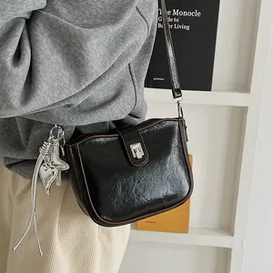 Detail of vintage black saddle bag with silver metal lock and decorative heart charm