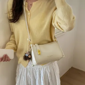 Detail of cream lychee leather Boston bag with gold lock and brown plush monster charm