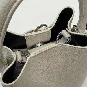 Dettaglio macro della borsa a secchiello beige in pelle martellata con chiusura magnetica