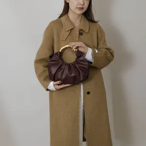 Détail d'un sac plissé en cuir vintage avec une élégante poignée en métal doré en U