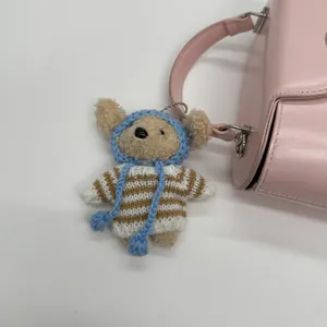 Detail eines süßen Plüsch-Anhängers mit blauer Strickmütze an einer rosa Tasche