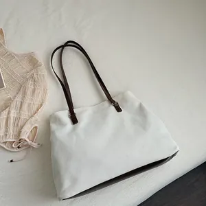 Detailed macro view of white canvas tote bag texture with premium brown leather strap