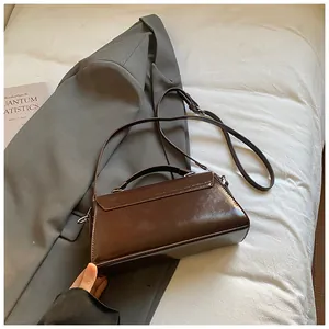 Top view of shiny dark brown satchel bag on grey blazer for professional office commute