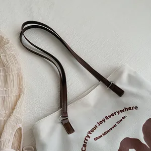 Detail of cream canvas tote bag with brown leather straps and inspirational typography