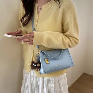 Detail of light blue faux leather Boston bag with gold hardware and plush monster charm