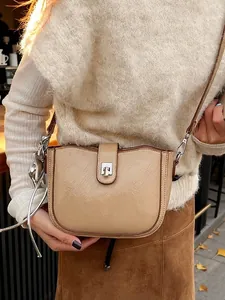 Chic light khaki saddle bag with metal buckle shown on model in a minimalist style