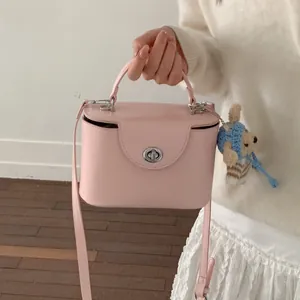 Detail der hellrosa Box-Tasche mit silbernem Drehverschluss und süßem Plüschbären-Anhänger