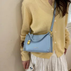Detail of light blue lychee pattern leather handbag with gold hardware on a model