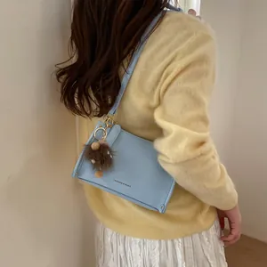 Close-up of light blue lychee pattern crossbody bag with cute brown plush pendant