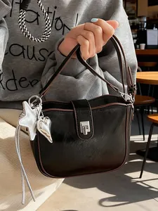 Classic black saddle bag with brown trim and silver charms in a stylish cafe setting