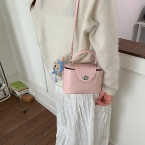Detail der rosa Koffer-Tasche mit silbernem Metalldrehschloss und braunem Bärenanhänger