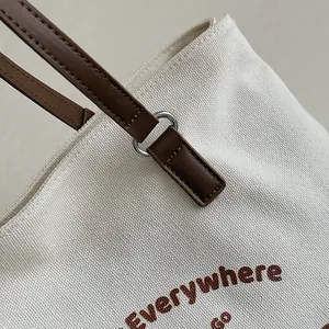 Close-up of canvas texture and brown leather handle stitching on the tote bag