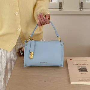 Detail of light blue pebble leather Boston bag with gold lock and plush monkey charm