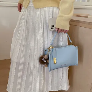 Detail of light blue pebble leather Boston bag with plush monster charm and gold hardware