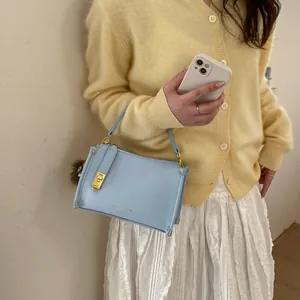 Detail of light blue lychee pattern handbag with gold lettering and brown fur ball charm
