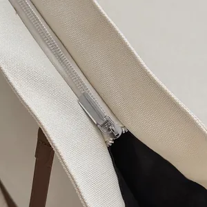 Detailed close-up of the silver metal zipper and durable canvas fabric on the tote bag